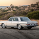 A silver 1971 Mercedes-Benz 300SEL parked in front of rocks, rear three quarter view